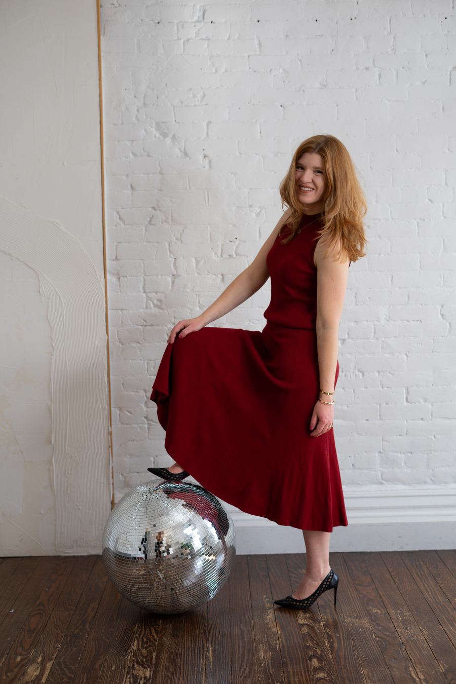 Kateryna Quinn, founder of aStash, in a red dress with a disco ball at her Fort Collins studio