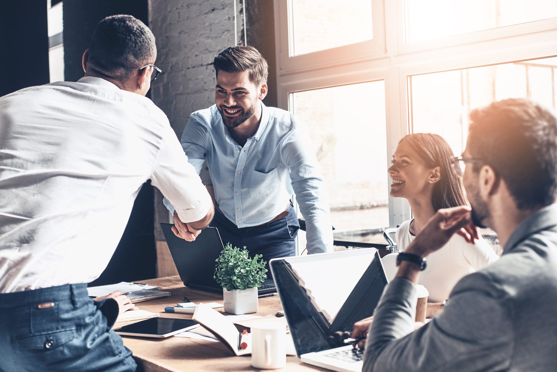 Business partners shaking hands across a desk