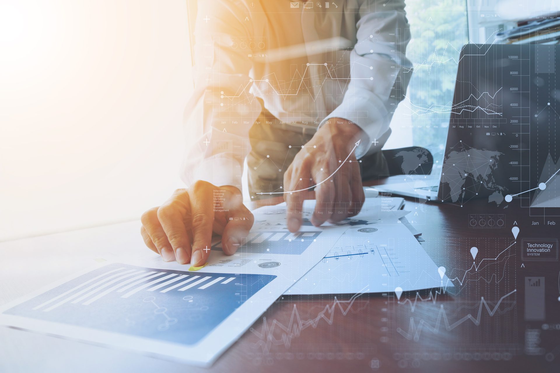 Hands reviewing printed charts beside a laptop
